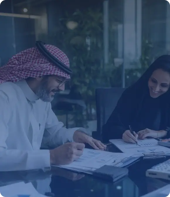 شخصان بزي عربي في اجتماع داخل مكتب حديث يتبادلان الأوراق في بيئة عمل تعاونية